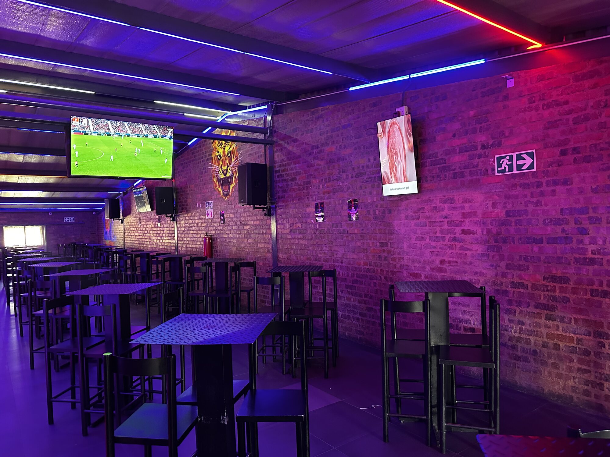 Sports lounge high tables under the big screens and tiger artwork at Cheeky Tiger Midrand