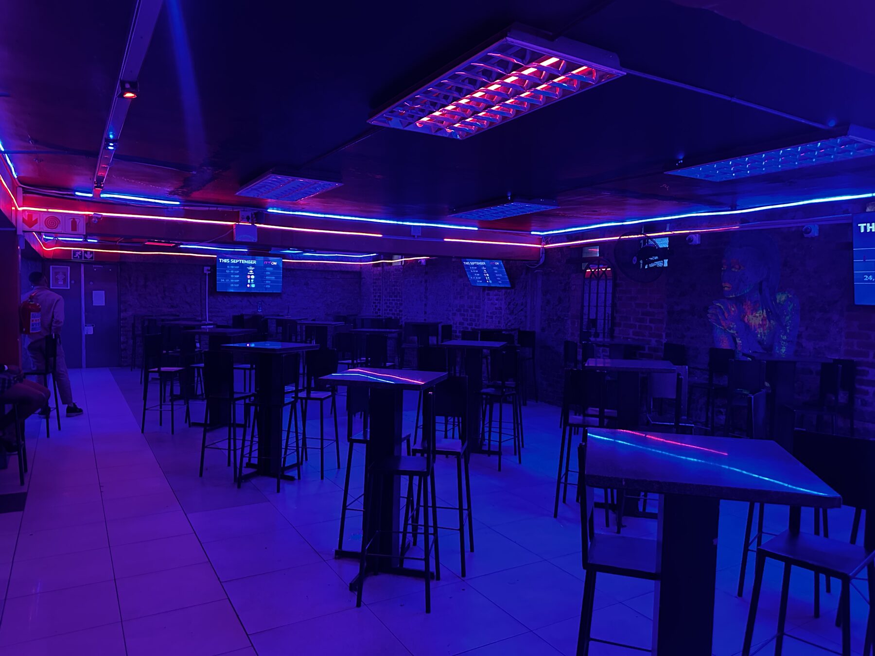 Seating area of high tables under the neon ceiling lines at Cheeky Tiger Diepkloof Hotel