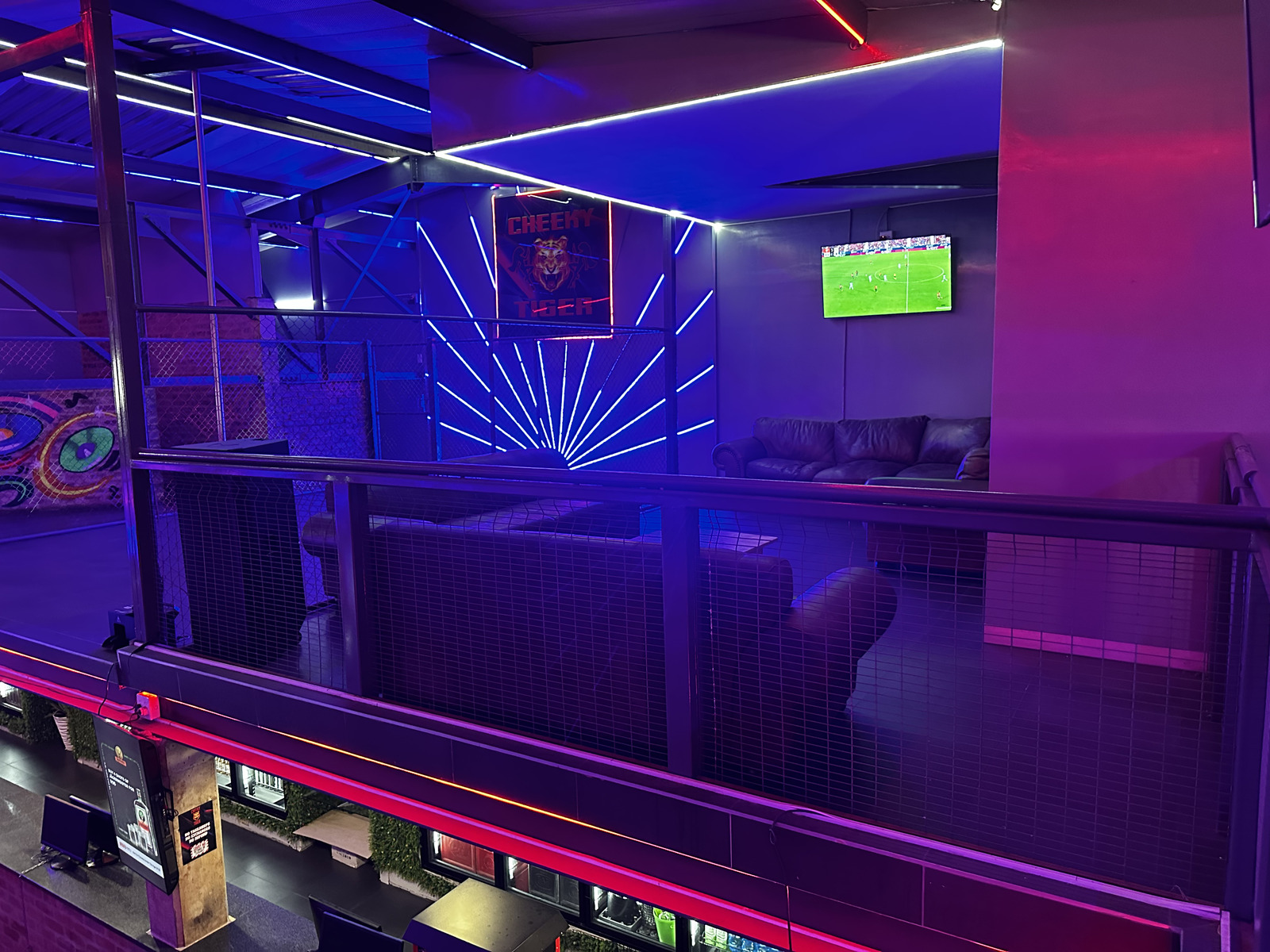 VIP lounge with leather couches under the neon Cheeky Tiger sign at Midrand