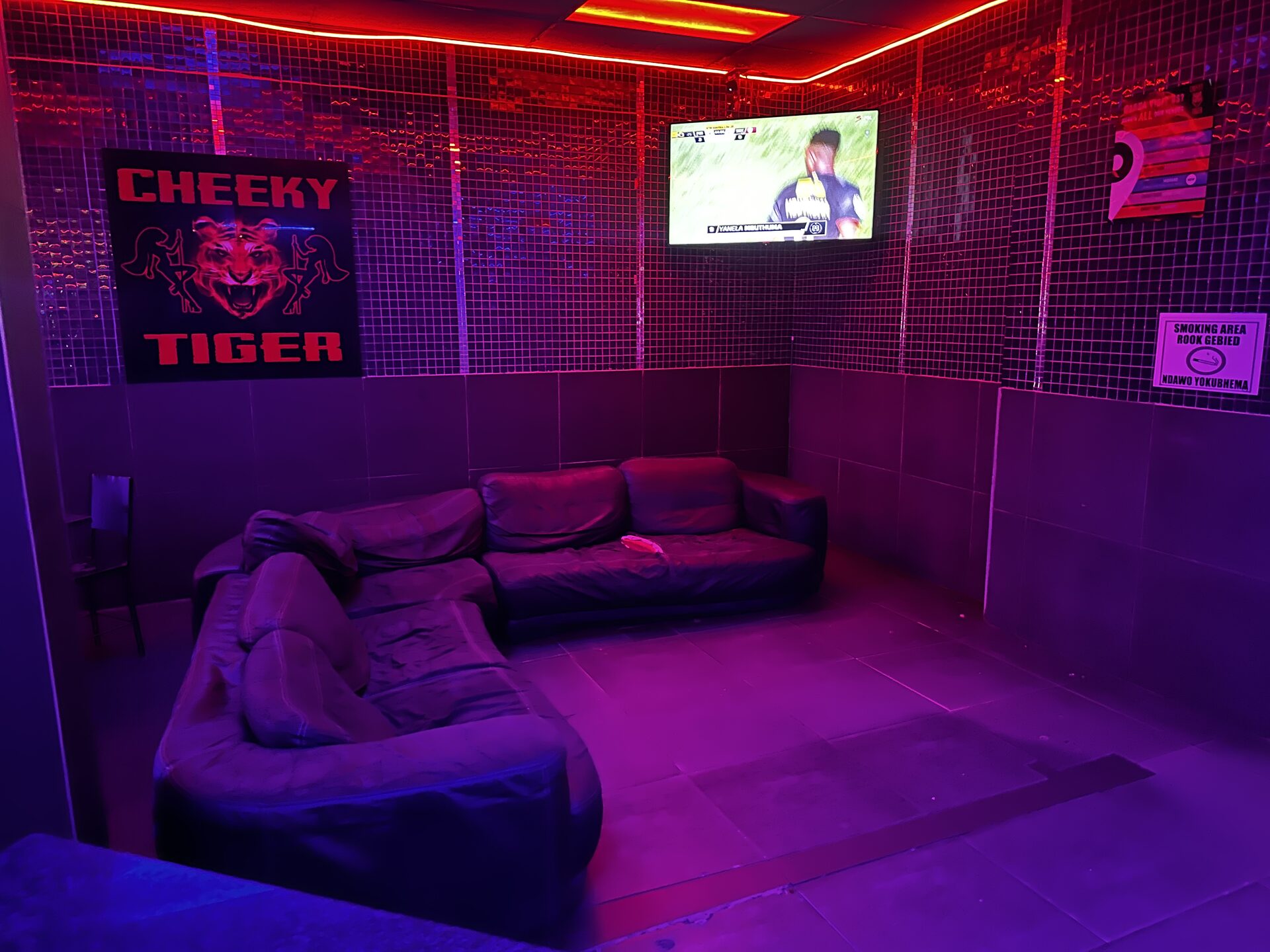 Smoking lounge with couches, screens and the Cheeky Tiger sign at Kempton Park