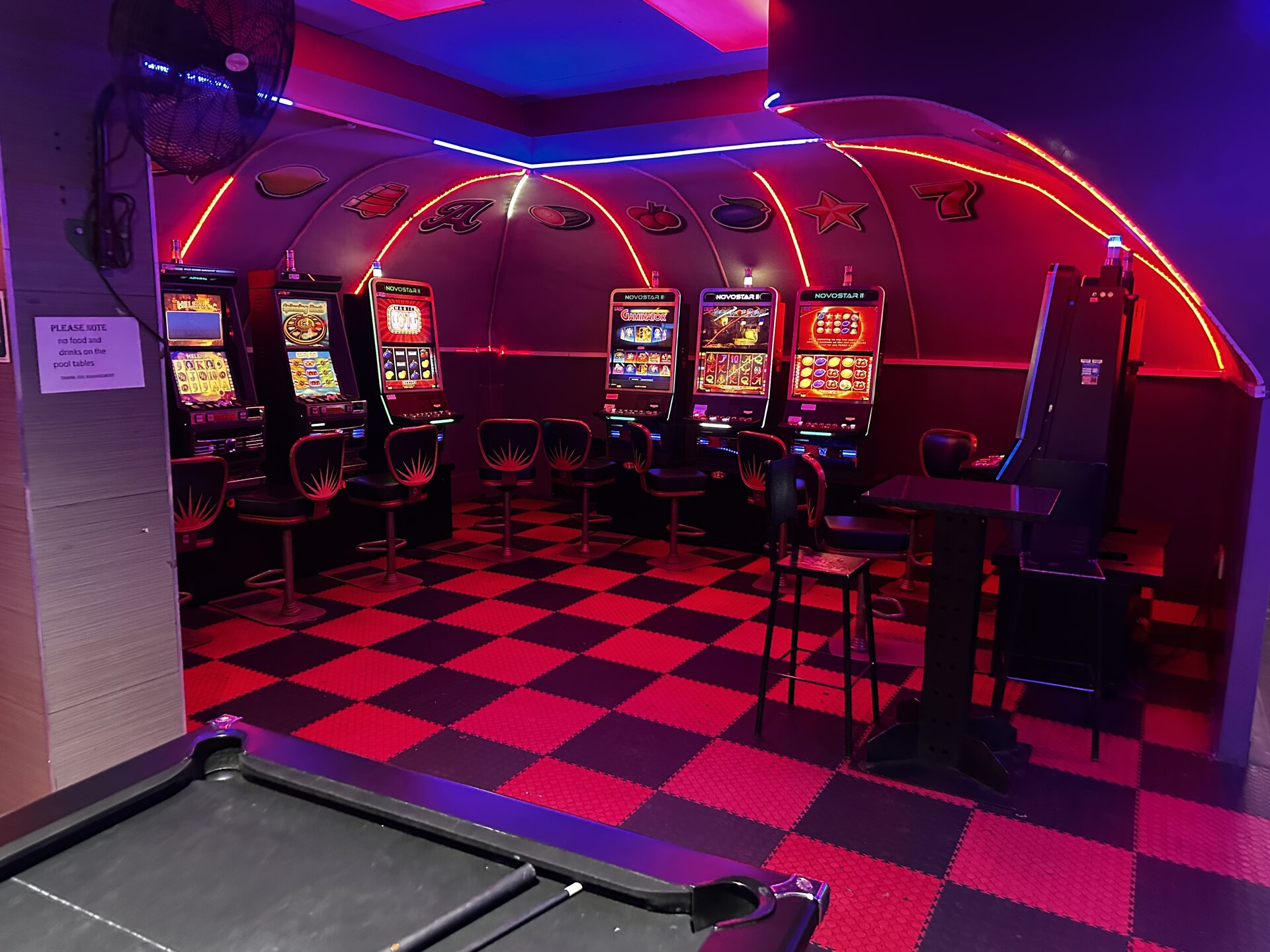 Gaming floor with slot machines under a red neon arch mural at Cheeky Tiger Kempton Park